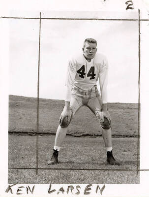 Ken Larsen (#44), center for the University of Idaho football team, crouching with his hands his knees.