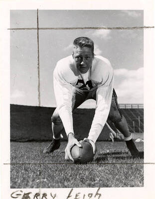Center for the University of Idaho football team, Gerry Leigh (#21), crouching with his hands on a football.