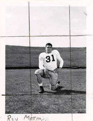Football player for the University of Idaho, Roy Mosman (#31) kneeling on the football field.
