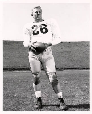 Varnell Neese (#26), a guard for the University of Idaho football team, standing on the field with a football.