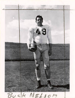Buck Nelson (#49), a fullback for the University of Idaho football team, standing on the field with a football.