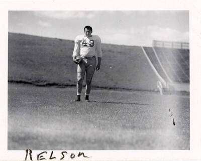 Buck Nelson (#49), a fullback for the University of Idaho football team, standing on the field with a football at a distance from the camera.