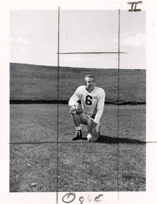 Jerry Ogle (#6), an end for the University of Idaho football team, kneeling on the field.