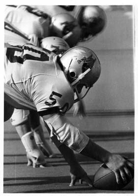 Number 50 for the University of Idaho football team prepares to snap the ball in the lineup during a football game.