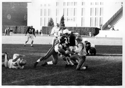 Three men get caught up in a tackle as the football floats next to them.
