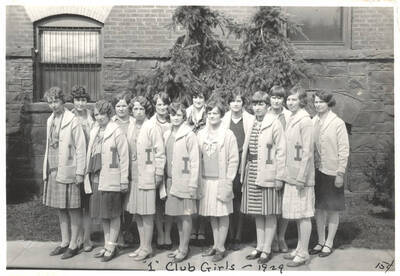 I Club members standing outside of the Women's Gym for a group photo. Caption reads ''I' Club Girls ~1929, 15 cents'.