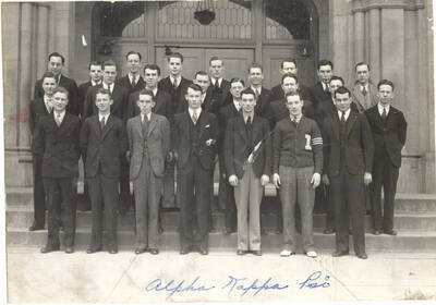 Alpha Kappa Psi members stand for a photo on Memorial Gym steps. Alpha Kappa Psi is a national professional commerce fraternity. Individuals identified as listed. Front: D. Kendrick, R. Lyons, M. Malin, L. Gaffney, L. August, C. Geraghty, W. Rich; middle: J. Holt, R. Herman, D. Linehan, S. Summers, W. Wilde, E. Hargraves, D. Barton, R. Ashbrook; back: J. Aram, L. Kraemer, T. Painter, J. Hannah, R. Jaggard, etc