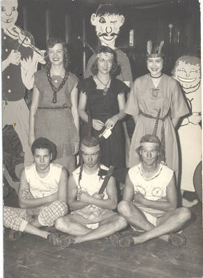 Unidentified greek residents dressed in Native American inspired clothing pose before cardboard cutouts.