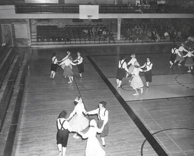 Small groups of women dance in group circles during the folk dance festival.