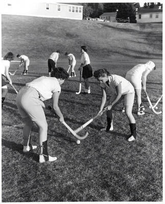 Women pair up to practice field hockey on MacLean field.