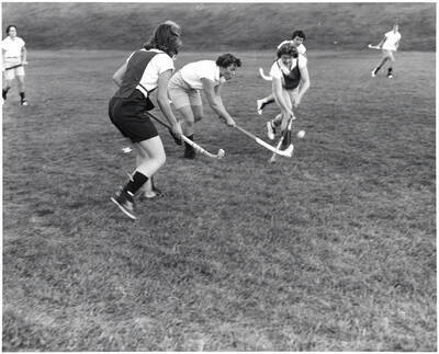 Women play field hockey on MacLean field.