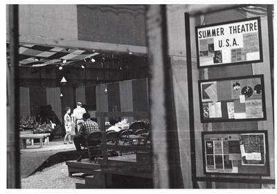 Summer Theatre company members rehearse inside the Field House. Newspaper clippings are framed on a wall with one of them reading: 'Summer Theatre U.S.A.'