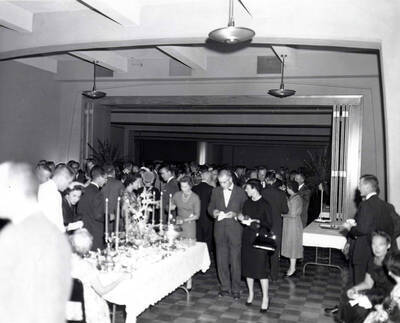 Attendees of the faculty reception stand with plates of food while engaged in conversation with each other.