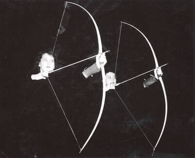 Two women draw back on their bows in archery class at the University of Idaho.