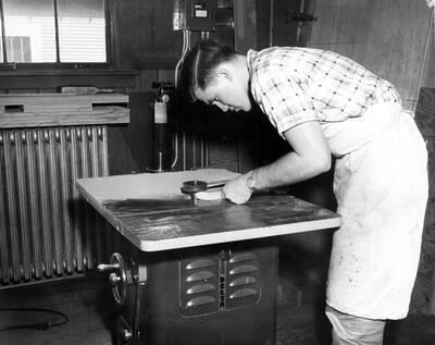 An Industrial Arts Education student holds a piece of wood to an edging machine to round off the edges.