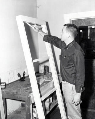 An Industrial Arts Education student paints a wooden frame.