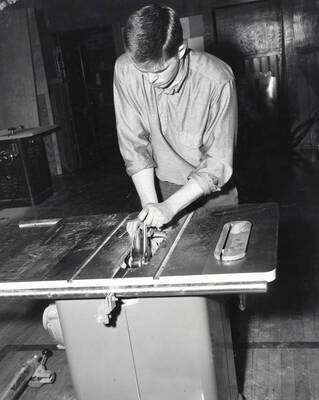 An Industrial Arts Education student cuts a piece of wood with a table saw.