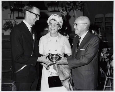 University of Idaho student Lonnie Steve Atchley receives the Theophilus outstanding senior award (a silver cup with his initials) from President Donald R. Theophilus and Cora Theophilus.