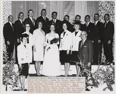 outstanding seniors, named at May Fete, pose for a group photo. Individuals identified as listed. Row 1: Marcia Ann Studebaker, Deanna Sue Solomon, Nancy Grubb Nelson, Carol Dianne Hussa, Janice Sennett Craig, Barbara Suter Henriksen, President D.R. Theophilus. Row 2: Robert Leeroy Cameron, John Irvin Sackett, Frederick George Fancher, Charles Russell Kozak, James Lee Johnston, Richard Norman Jennings, James Ralph Fields, Larry Bruce Grimes, Gerald Walden Hyettig, and Larry Allen Kirkland.