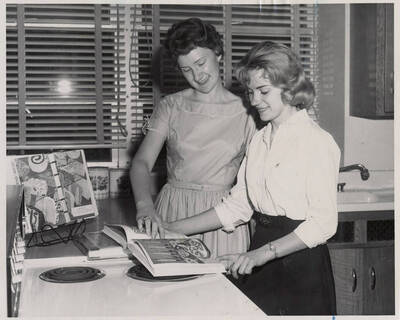 Carmon Witteman and Marilee Allen review cookbooks in the Home Economics development lab.