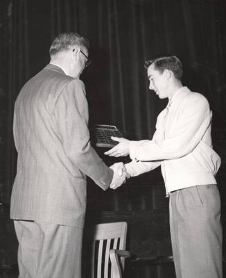 University of Idaho student Ernest Bedke, president of Sigma Alpha Epsilon fraternity, accepts the Interfraternity Council trophy from University of Idaho President Jesse E. Buchanan.