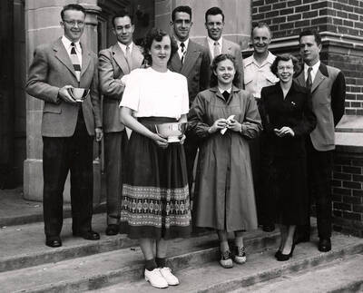 Nine seniors pose for a group photo outside of the Administration Building after receiving their awards. Individuals identified as listed. Front: Joanne Hofmann, Geraldine M. Early, Diana Hooper; back: Max Ririe, Leonard Winkle, Harry Howard, Richard Thomas, Robert Day, and Willard Barnes
