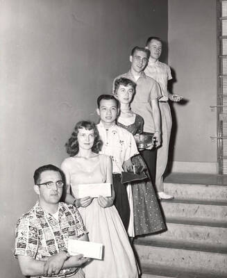 Outstanding seniors stand in a staggered formation on the stairs of the Memorial Gymnasium after receiving their awards. Individuals identified as listed. Left to right: Donald Isaacson, Maureen Louise Abbott Mix, Ronald Han Tan, Joyce E. Genoway, Thomas R. Warner, and James A. Steele