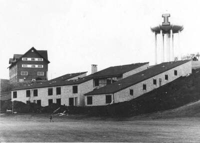 Distanced photo of Sigma Chi house under construction, located at 735 Nez Perce Drive. An individual walks past the building site in the foreground.