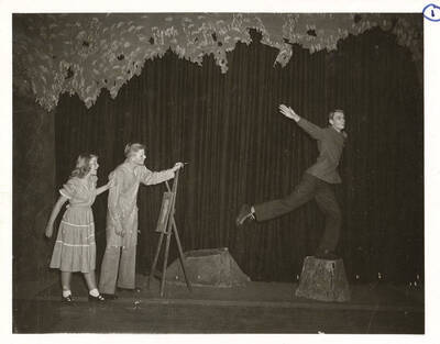 Students from l-r: Colleen Christensen as Margaret, William Davidson as Mr. Dearth, and Guy Terwilleger asMr. Coade. Terwilleger poses upon a stump during the University of Idaho production of a scene in 'Dear Brutus.' An ASUI production directed by Jean Collette in the University of Idaho Auditorium.