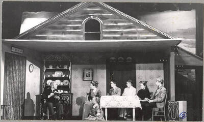 From l-r: Richard Pennell as Mr. Hyde, Marjorie Dean as Mama, Pat Blessinger as Dagnar, Mac Parkins as Nels, Lillian Bowler as Trina, Polly Garst as Christine, and Richard Peterson as Papa. Mr. Hyde reads a book to the rest of the party in a scene of Idaho drama's production of 'I Remember Mama.' An ASUI production directed by Jean Collette in the University Auditorium.