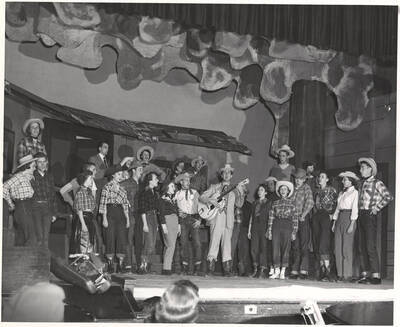 Individuals identified on mount; Idaho drama students perform a group singing scene during production of the play, 'Sing, Senator, Sing.' An ASUI production written by Geoffrey Coope, Theodore Sherman, & music Hall Macklin (all UI teaching faculty), directed by Jean Collette in the University Auditorium.