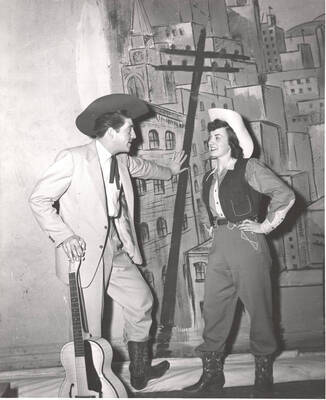 Charles Lafollette and Phyllis Ralson talk before production of the play, 'Sing, Senator, Sing.' An ASUI production written by Geoffrey Coope, Theodore Sherman, & music Hall Macklin (all UI teaching faculty), directed by Jean Collette in the University Auditorium.