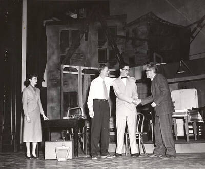 Willie, played by Tom Wright, shaking hands with his neighbor's son during a drama production of 'Death of a Salesman'. ASUI production in the University Auditorium and directed by Jean Collette.