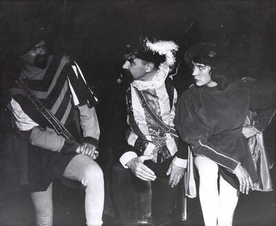Three cast members in costume perform a scene together during a drama production of 'Kiss Me Kate'. Cast includes Larry Black, Joan Fisher, Bert Allen, Mary Jane Milbrath, Austin Bergen, Charles Tovey,  Corolie Davis, Dick Cripe, Dwight Patton, Cliff cook, Nathan Yost, Ed Vandervort, Wayne Benson, Graham Knox, Malcolm Alexander, Dick Katzenberger, Bob Moe, and Tom Baldwin. ASUI productions directed by Jean Collette in the University Auditorium.