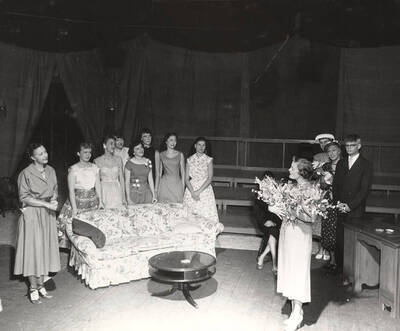 Directed by Jean Collette for Summer Theatre in the Field House. A group of people looking at a woman hold a bouquet of flowers in 'Goodbye My Fancy.'