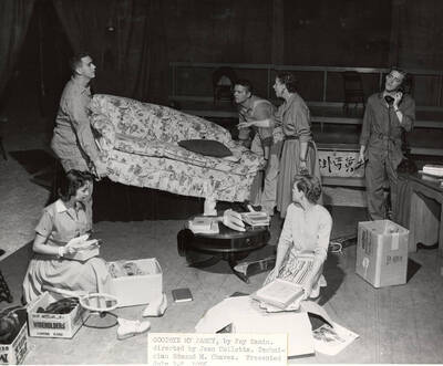 Directed by Jean Collette for Summer Theatre in the Field House. Two men moving a couch and a woman directing them. A man on the phone. Two women sitting on the ground in 'Goodbye My Fancy.'