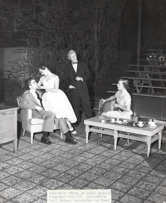 A woman sitting on a man's lap. Another woman sitting on the couch looking at the couple. A man looking at the woman sitting on the couch. 'Affairs of State' directed by Cecil Matson for Summer Theatre in the Field House.
