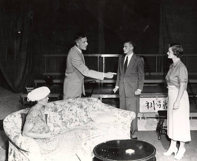 A man pointing at a woman. A woman sitting on the couch looking at the other woman. Another man looking at the man pointing. Summer Theatre in the Field House directed by Jean Collette. Summer Theatre in the Field House directed by Jean Collette.