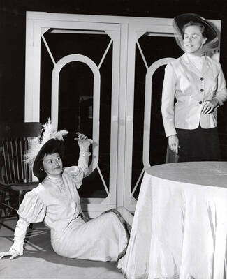One woman sitting on the ground and another looking down at her. Summer Theatre in the Field House directed by Donald Hill.