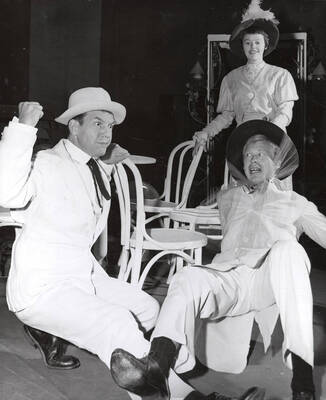 One man holding up his fist another man backing away and a woman in the background amused by the scene unfolding. Summer Theatre in the Field House directed by Donald Hill.