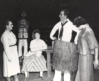 Agnes Risetter, Maybelle Clinkosky, Tony Matson. A man holding a grass skirt up to himself and three women looking at him. Summer Theatre in the Field House directed by Cecil Matson.