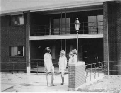 Four women stand outside the entrance of Alpha Gamma Delta house, located at 727 Nez Perce Dr., 1967 or later.