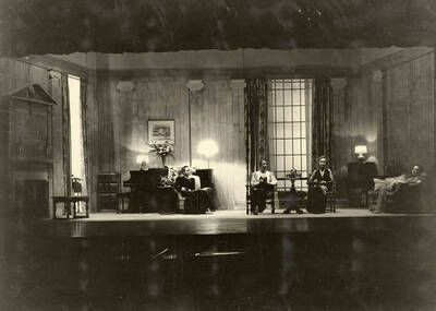 During the drama production of "Dangerous Corner," women sit on stage. Cast: Robert Herrick as Gordon Whitehouse, Dorothy Pierce as Freda Chatfield, Eldred Stephenson as Robert Chatfield, Alline King as Olwen Peel, Paul Selby as Charles Stanton, Nina Varian as Betty Whitehouse, Ethlyn O'Neal as Maud Mockridge.  Directed by Fred Blanchard.