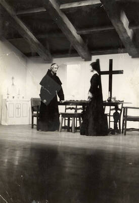 A man and woman stand on stage during the drama production of "Night Over Taos." Cast: Eldred Stephenson as Pablo Montoya, Bill Cherrington and Don Tracy as Frederico and Felipe, Malcolm Renfrew as Martinex, Murva James as Diana, Marian Swanson as Dona Josefa and Erma Lewis as Veri. ASUI production directed by Fred Blanchard in the  University Auditorium.