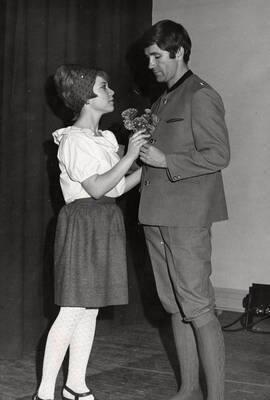 A woman and man hold flowers during the drama production of "The Bartered Bride." Presented by Music and Drama department, directed by Forrest Sears. Music director Charlie Walton. Staged in the University Auditorium.
