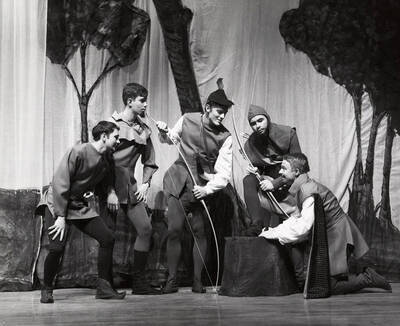 Men huddle on stage with bows during the children's theatre production of "Ballad of Robin Hood." Directed by Walter Brennen.
