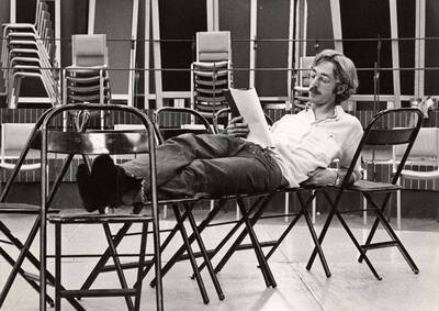 A man lays across some chairs, reading his lines, during the drama production of "You're a Good Man, Charlie Brown." Summer Theatre directed by Edmund Chavez in the Kiva.