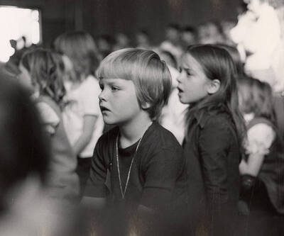 Kids sit in the audience and watch a drama production.