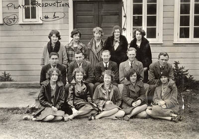 A group of men and women sit together during an advanced play production. They are outside of the U-Hut.