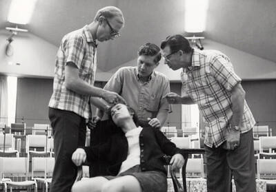 Three men look at a woman's hair during a Summer Theatre rehearsal in the Kiva.